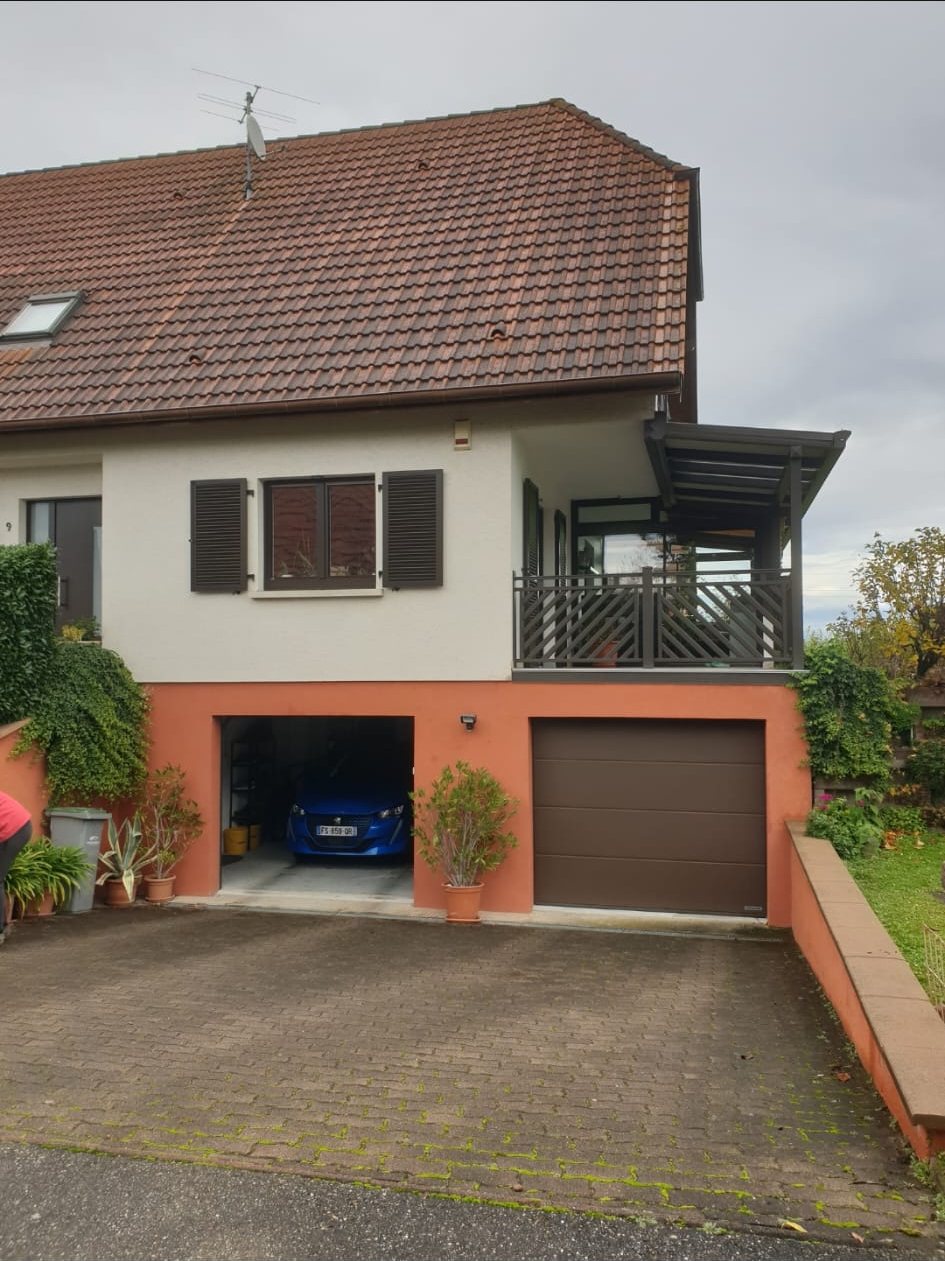 Avant : maison sur garage, toiture brune.